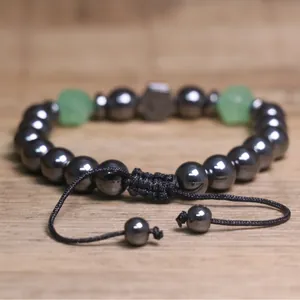 Detailopname van een handgeweven armband met hematiet kralen en groene steenaccenten