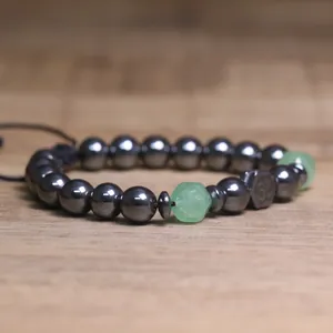 Detailopname van hematiet kralenarmband met groene gefacetteerde stenen en een Om-bedeltje