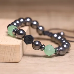 Detail van hematiet armband met groene stenen en zwarte kraal met het Om-symbool
