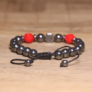 Detail van een gevlochten armband met 8 mm hematiet en rode gefacetteerde kralen