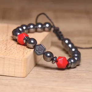Detail van handgemaakte 8 mm gefacetteerde hematiet gevlochten armband met rode accenten.