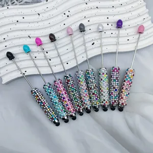Detailed view of multi-colored rhinestone DIY beaded stylus pens on white wavy plate