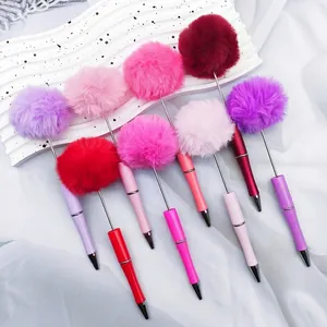 Various colorful fluffy pompom pens arranged on white decorative wave board