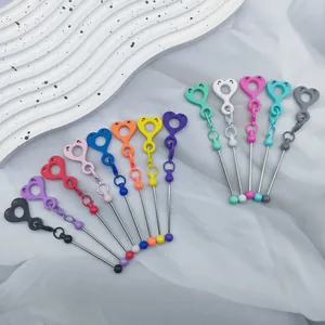 Gros plan de charms smiley cœur DIY colorés avec tiges en métal sur tissu blanc