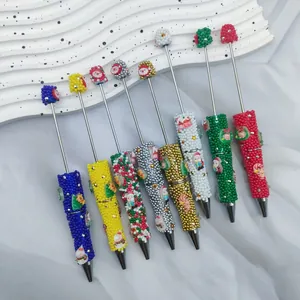 Primer plano de bolígrafos de cuentas navideñas DIY con dijes de Papá Noel y muñeco de nieve