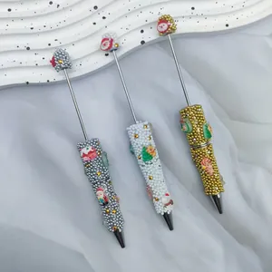 Detalle de bolígrafos navideños DIY con cuentas y dijes de Papá Noel y muñeco de nieve