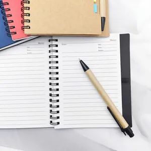 Macro detail of open spiral kraft paper notebook with pen and color index sticky notes