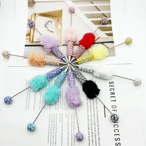 Detailed view of colorful beaded ballpoint pens with plush fur pom-poms and gems.