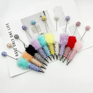 Detailed view of colorful pearl and rhinestone ballpoint pens with fur pom-poms
