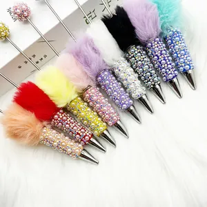Close-up of decorative ballpoint pens with faux fur pom-poms and rhinestones