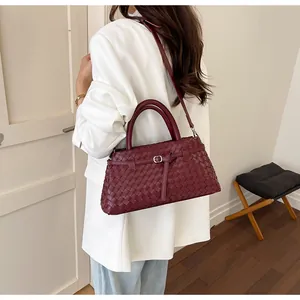 Detailansicht einer burgunderfarbenen handgewebten Handtasche, getragen von einem Modell
