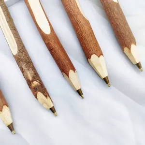 Close-up detail of eco-friendly natural bark wooden branch ballpoint pens with metal tips.