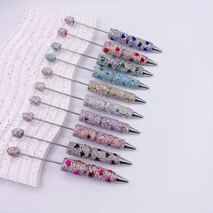 Gros plan de stylos à bille luxueux avec perles en strass et cœurs colorés