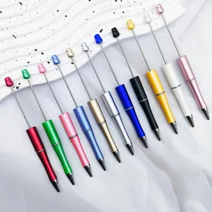 Array of colorful pearlized DIY beadable ballpoint pens on a white wavy background