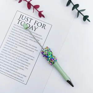Macro detail showing colorful candy sprinkle decorations on a light green DIY beaded pen.