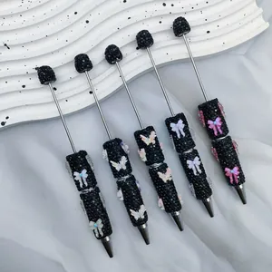 Elegant DIY black rhinestone beaded pens featuring colorful butterfly and bow charms