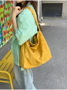 Vue détaillée d'un grand sac cabas jaune en daim porté par un mannequin dans un cadre extérieur