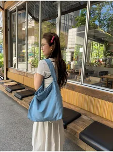 Une femme portant un grand sac cabas en faux daim bleu clair dans un café lumineux.