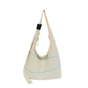 Detail view of a cream hobo shoulder bag featuring mint green double zippers and wide strap.