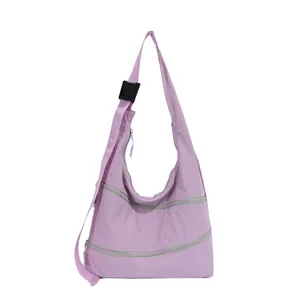 Front view of lilac nylon hobo bag featuring three horizontal silver zippers.