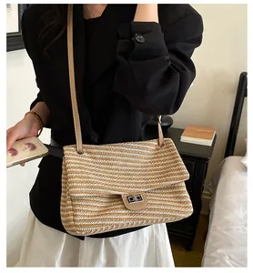 Elegante bolso de hombro de paja tejida a rayas llevado por una modelo en interiores