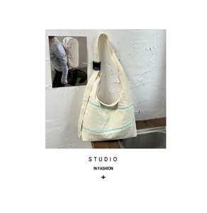 Cream canvas shoulder bag with dual mint green zippers and adjustable strap