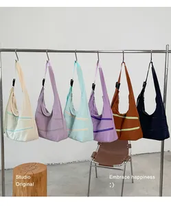 Row of colorful minimalist nylon hobo shoulder bags on a rack in a studio setting.