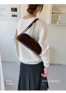 Model showcasing a dark brown suede bowling baguette shoulder bag from a back view.