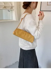 Minimalist yellow bowling baguette bag shown being worn as a stylish underarm shoulder accessory
