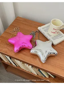 Borse da sera lucide a forma di stella in acrilico rosa e argento su scaffale in legno