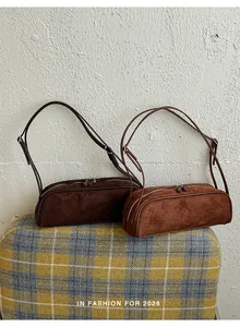 Two stylish brown suede bowling baguette bags displayed on a yellow plaid ottoman stool