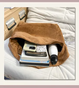 Vue détaillée de l'intérieur d'un grand cabas en daim marron avec objets essentiels.