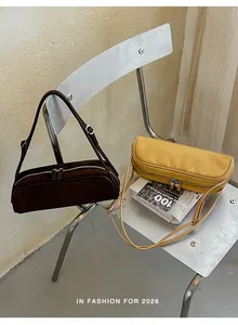Close-up of two stylish suede bowling bags in brown and yellow displayed on a modern chair.