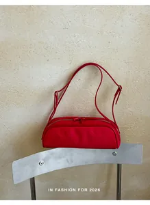 Minimalist red bowling baguette handbag displayed on a sleek modern metal chair.