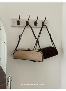 Elegant suede bowling bags in camel and brown colors hanging on hooks for styling