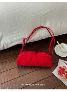 Stylish vibrant red bowling baguette shoulder bag displayed in a lifestyle setting
