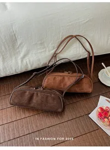 Chic brown and caramel suede bowling shoulder bags displayed on a warm wooden floor