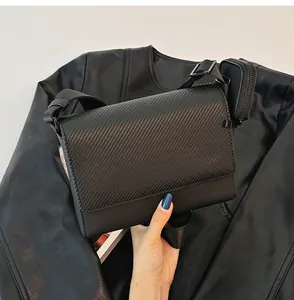 Vista detallada de un bolso de hombro negro texturizado con un mini estuche a juego.
