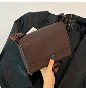 Primer plano de bolso bandolera marrón con mini estuche extraíble en la correa.