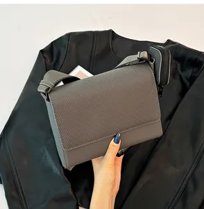 Detalle de bolso bandolera gris con solapa texturizada y estuche pequeño a juego en correa