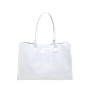 Detalle del bolso tote de PVC blanco con diseño de texto 'TOTE BAG' en relieve