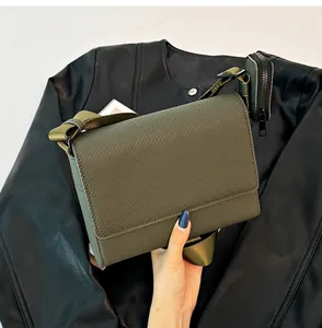 Primer plano de bolso bandolera verde oliva texturizado con correa y bolsa pequeña a juego.