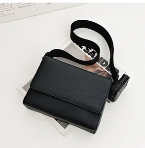 Detalle de un bolso bandolera negro minimalista con solapa texturizada y estuche desmontable.