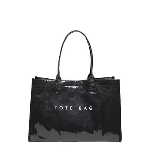 Vista detallada del bolso tote de PVC negro texturizado con el impreso TOTE BAG