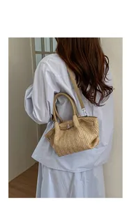 Elegante bolso de hombro de paja tejida beige para mujer en un ambiente informal de viaje.