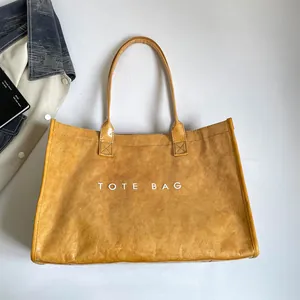 Detalle de bolso tote de PVC amarillo con textura rugosa e impresión en blanco.