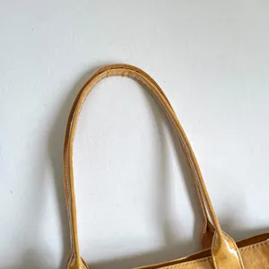 Primer plano detallado del asa de PVC duradera de este elegante bolso amarillo