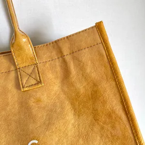 Vista detallada de un bolso tote de PVC amarillo texturizado con costuras de alta calidad