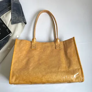 Vista detallada del bolso de mano de PVC amarillo brillante con textura y asas largas