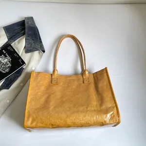 Detalle de la capa interna amarilla y la cubierta de PVC transparente del bolso tote